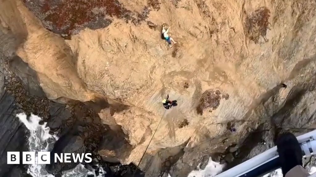 Moment person clinging to cliff is rescued by helicopter