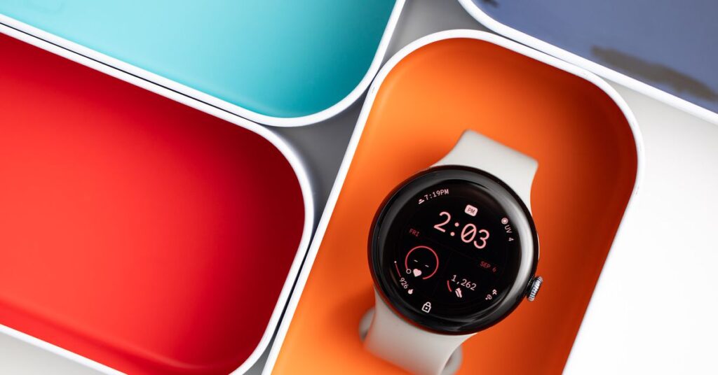 The Google Pixel Watch 3 resting in an orange case box surrounded by other colorful boxes.