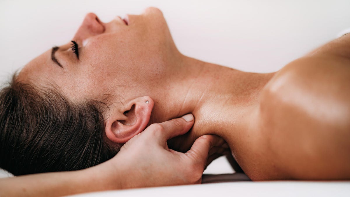 A side view of a person getting the back of their neck massaged near their lymph nodes.