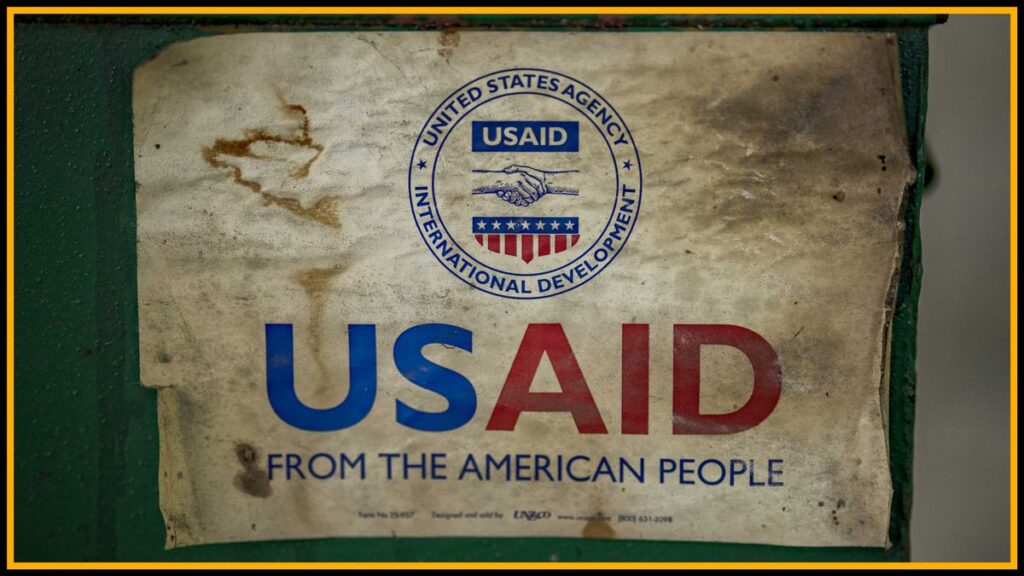 A worn USAID sign on a green rusty box