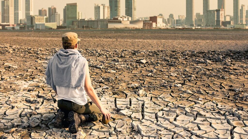 A man in the desert looks at the city after the effects of global warming.