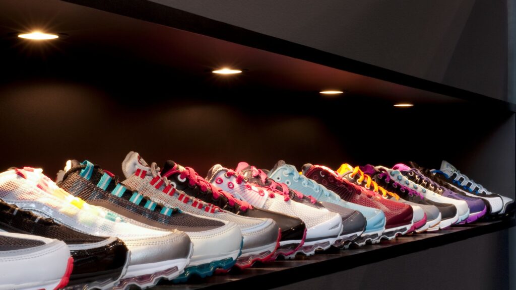 A variety of running shoes displayed in a shop under warm downlights