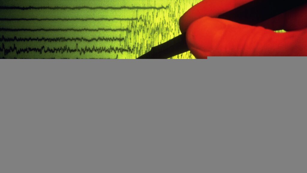 a person points to an earthquake seismograph