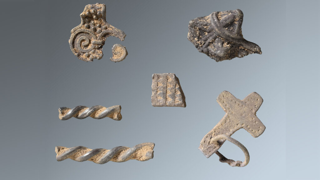a collection of metal Viking artifacts including a cross-shaped pendant